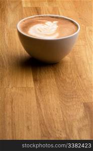 A cappuccino with latte art on a wooden table