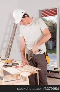 A carpenter drilling with a hand drill in a plank of wood