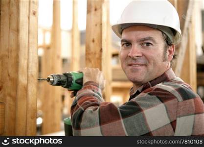 A carpenter using a battery powered drill on a construction site.