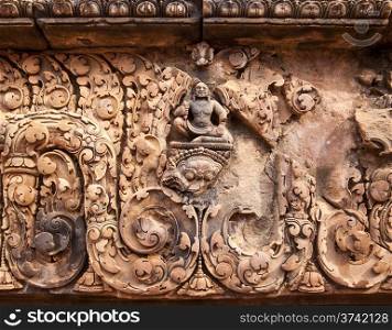 A carving of Buddha amidst other details above an entrance to one of the smaller buildings at the Banteay Srei temple near Angkor Wat.&#xA;