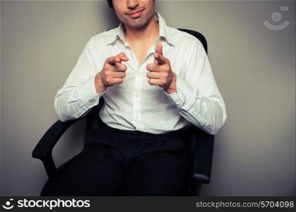 A casual and happy young businessman is sitting in an office chair