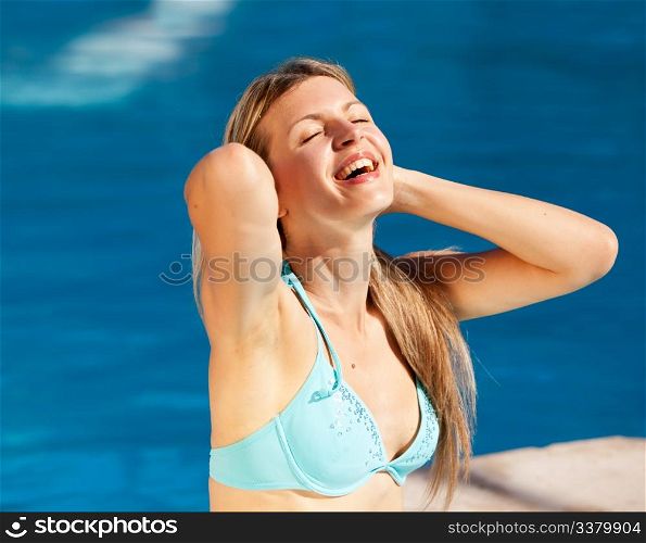 A caucasian blond woman relaxing at an outdoor pool