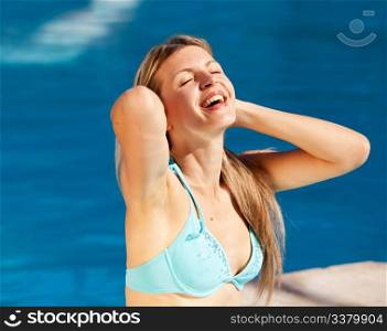 A caucasian blond woman relaxing at an outdoor pool
