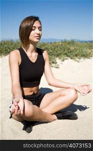 A caucasian girl practicing yoga on the beach