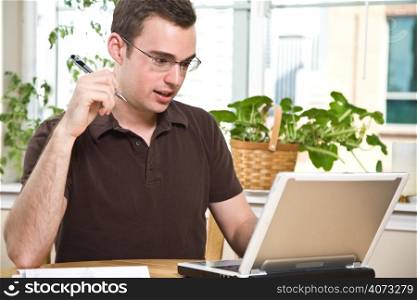 A caucasian man paying the bills by online banking at home