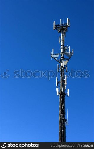 A cell phone tower rises against a blue sky.