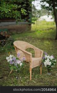 A chair in the garden among flowers and trees.. A wicker chair in the house garden 2797.