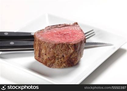 A chateaubriand or tenderloin steak on a plate with a steak knife and fork