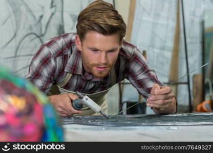 a cheerful jeweler soldering at work