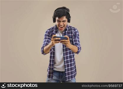 A CHEERFUL TEENAGER PLAYING VIDEO GAME ON MOBILE PHONE