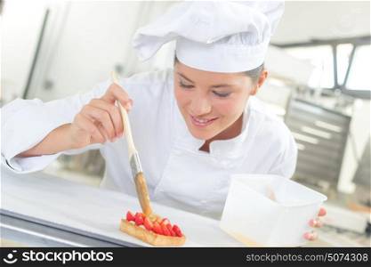 a chef glazing strawberry tart