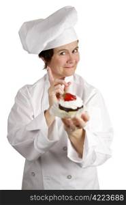 A chef holding a strawberry cheesecake tart and wagging her finger NO. Isolated on white.