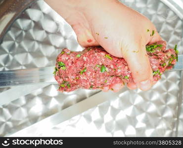 A chef making shish kebab of red meat with parsley over metal plate