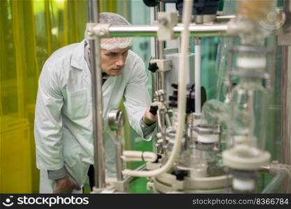 A chemist or apothecary who extracts cannabis, CBD oil, and tinctures using chemical processes. Medical cannabis product manufacturing facility. Cannabis oil extraction machine and equipment.. Scientist apothecary extract using cannabis extraction machine in laboratory.