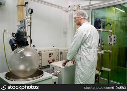 A chemist or apothecary who extracts cannabis, CBD oil, and tinctures using chemical processes. Medical cannabis product manufacturing facility. Cannabis oil extraction machine and equipment.. Scientist apothecary extract using cannabis extraction machine in laboratory.