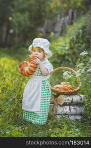 A child eats a fresh loaf in the garden.. Little girl in a suit of food boy in the garden 4636.