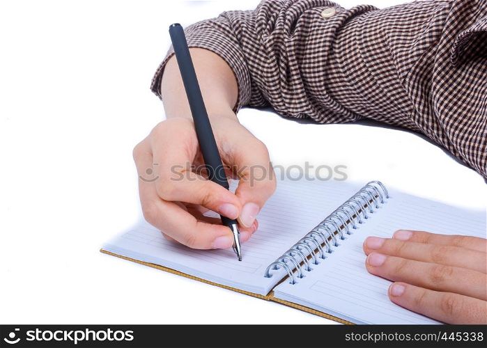 A child hand is writing with pen on a spiral notebook on white background