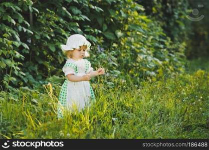 A child in a dress with apron and bonnet on.. A child walks in the summer garden 4646.