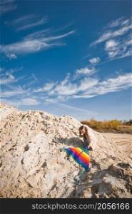 A child launches a rainbow kite.. A child is playing with a kite in the sand 3331.