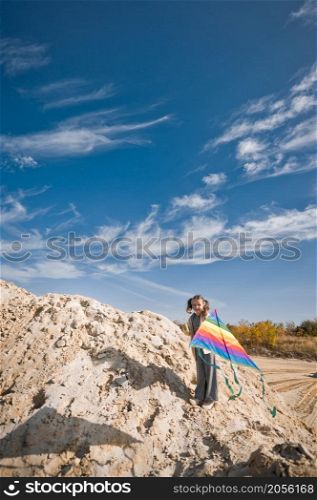 A child launches a rainbow kite.. A child is playing with a kite in the sand 3333.