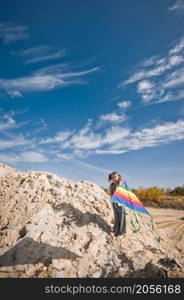 A child launches a rainbow kite.. A child is playing with a kite in the sand 3333.