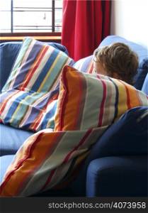A child sitting behind a colourful striped pillow