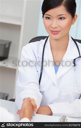 A Chinese Asian female medical doctor shaking hands at a meeting in her hospital office