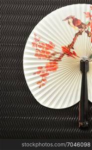 A chinese hand fan isolated on a black background