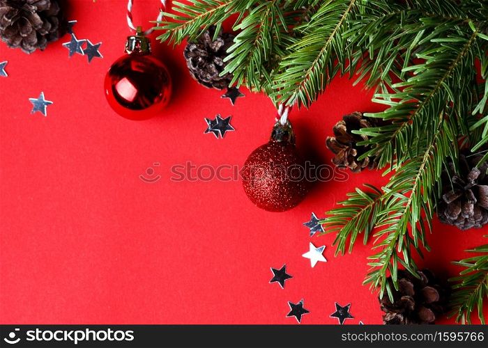 a christmas background. Christmas tree twigs, Christmas balls and cones on a red background