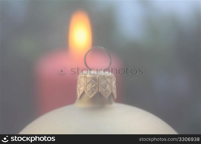 A christmas ornament in soft focus, candle in background