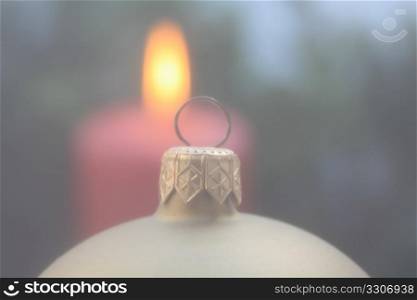A christmas ornament in soft focus, candle in background