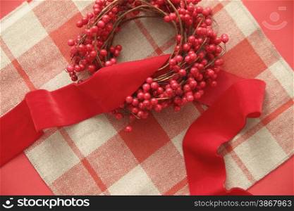a Christmas wreath with red berries and a velvet ribbon on a plaid background