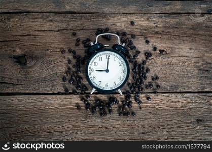 A clock and coffee beans on the desk top view