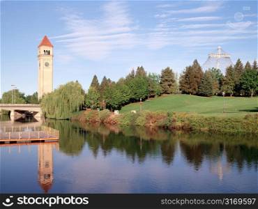 A Clock Tower And Trees Reflected In A Still Pond