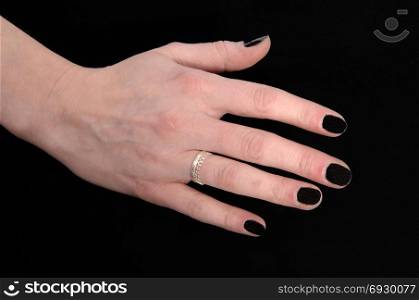 A close up image of the hand of a young woman with her black fingernails and a ring, isolated for black background