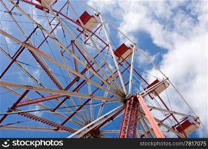 A close up of a ferris wheel with a partially clouded sky