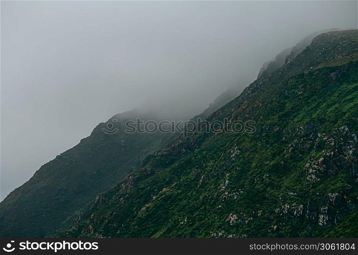 A close up of a giant green mountain surrounded by the mist in europe with copy space