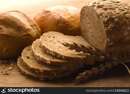 A close-up of a new-baked loaf of bread with a wheat head.