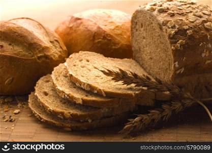 A close-up of a new-baked loaf of bread with a wheat head.