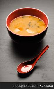 A close-up of a spoon and a soup plate with delicious miso soup.