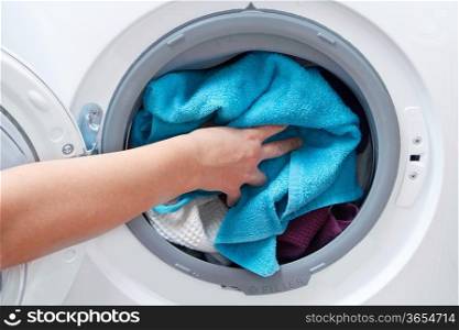 A close up of a washing machine loaded with clothes isolated on white background
