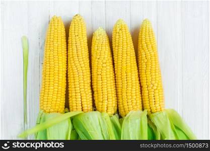 A close-up of corn produced in a rustic garden, on a white wooden village desk, shallow depth of focus. The concept of agro, agriculture. A close-up of corn produced in a rustic garden