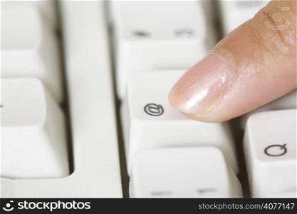 A close up of finger pressing the @ button