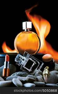 A close-up of two bottles of male and female perfume and cosmetics against a flaming background.