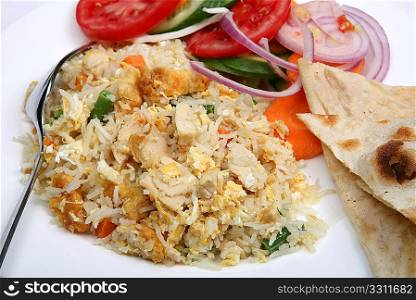 A close-up view of chicken fried rice with a salad and slices of nan bread.
