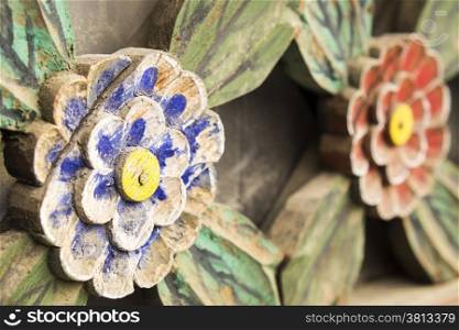 A close-up view of the architectural detail of painted wooden flowers on a window screen in a Buddhist temple in Korea.