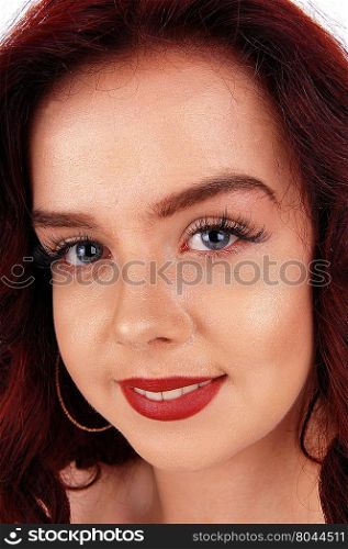A closeup image of a beautiful face of a young woman with red hairand blue eye&rsquo;s, smiling.
