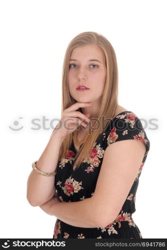 A closeup image of a gorgeous blond woman standing in a dress withone hand on her chin, isolated for white background