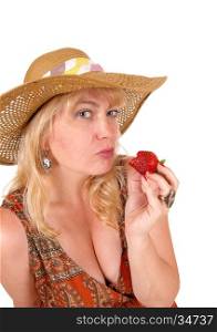 A closeup image of a nice woman eating a big strawberry with blue eye'sand a straw hat, isolated for white background.