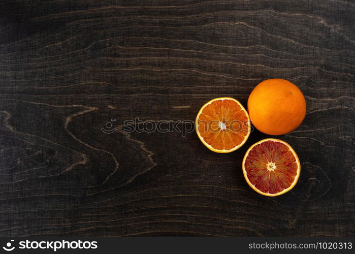 A closeup photo of vibrant organic blood oranges on a dark background with copy space.